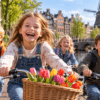 Happy children cycling beside a Dutch canal, with traditional houses, tulips and a windmill in the background.