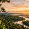 Amazon rainforest at sunrise with a winding river surrounded by dense green forest, illustrating Brazil’s fall in Amazon deforestation alerts.
