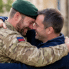 An emotional reunion between an Army veteran in military uniform and a stem cell donor, embracing warmly with smiles of gratitude and relief.